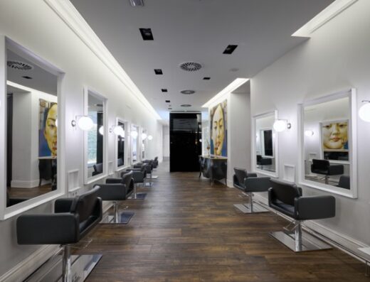 Sala Principal De Rubén Hernáez Peluqueros En Logroño, Con Dos Filas De Puestos Enfrentados Y Espejos De Marco Blanco